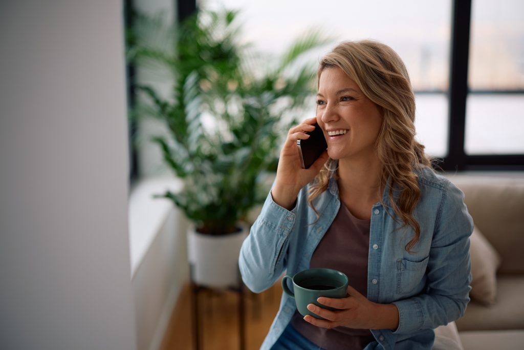 a happy woman smiling while making a phone call in at home